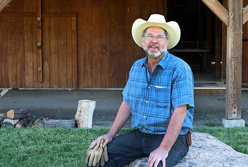 photo of howard johnson in working clothes sitting in front of his barn