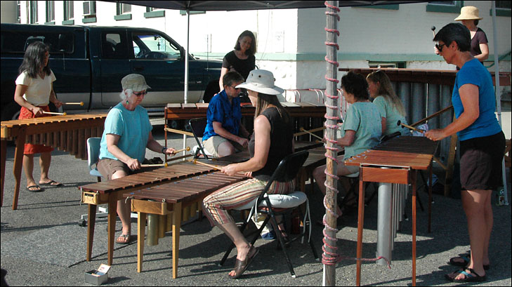 photo of women playing marimbas under market tent